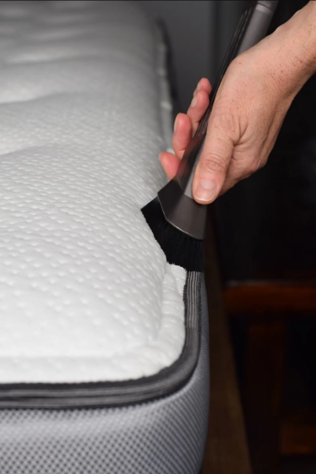 Kefés porszívófejjel tisztítják egy matrac szegélyét